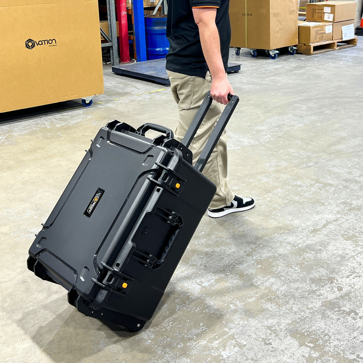 Bruce Bravo BV-675336 wheeled waterproof hard case being transported by handle in a warehouse